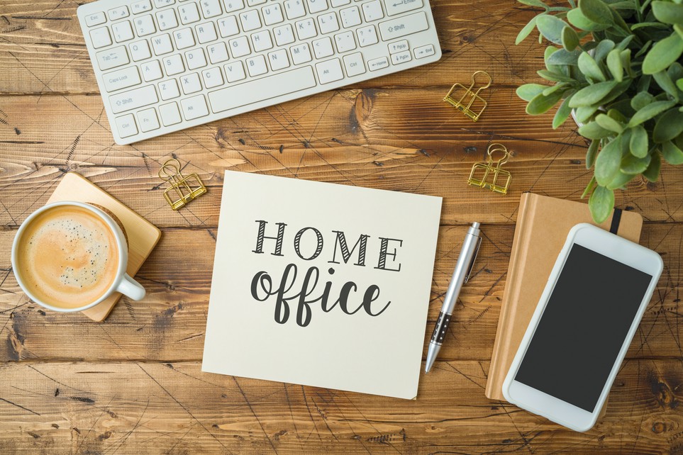 Schreibtisch mit Arbeitsutensilien und Zettel mit dem Wort Home Office darauf